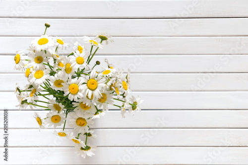 Camomile flowers. Bouquet of daisy on a white wooden background. Flat lay, top view, copy space
