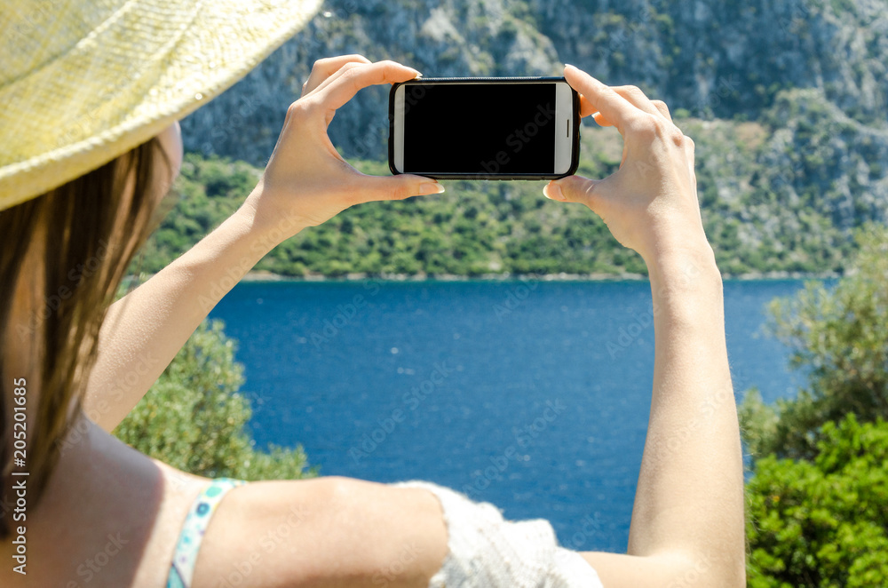 Woman in summer hat holding white smartphone on sea water on yacht sunny day background copy space top view weekend holidays rest