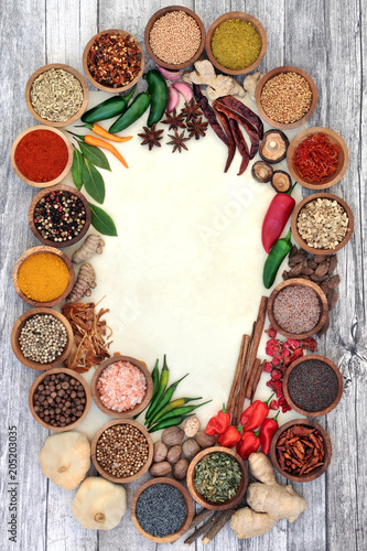 Herb and spice abstract background border with fresh and dried herbs and spices on rustic wood and parchment paper. Top view.