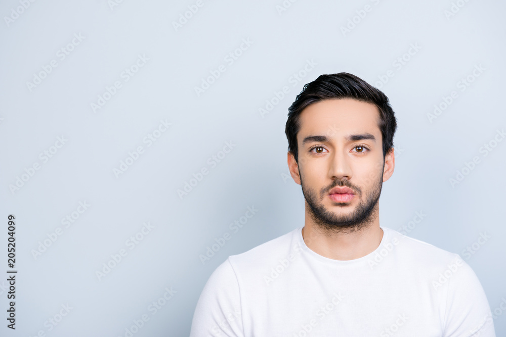 Portrait with copy space empty place of attractive strict guy with bristle black hair in white outfit looking at camera isolated on grey background Portrait with copy space empty place of attractive strict guy with bristle black hair in white outfit looking at camera isolated on grey background