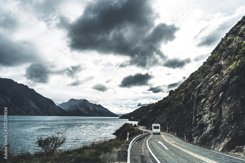 Dramatic photo style - The stunning landscape of road beside the ocean with a cloudy and mountain scene.