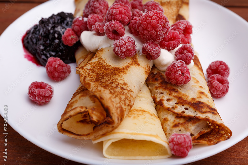 tasty home made pancakes with ice cream on craft wood table decorated with jam, raspberries and nuts tasty home made pancakes with ice cream on craft wood table decorated with jam, raspberries and nuts