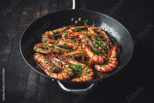 Shrimps fried in a pan. Classic recipe - parsley, garlic, chilli peppers and white wine.