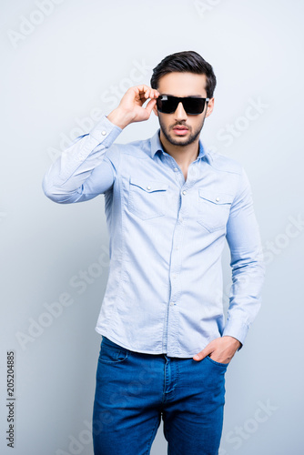 Vertical portrait of cool rich macho in elegant outfit black glasses holding eyelet posing looking at camera isolated on grey background