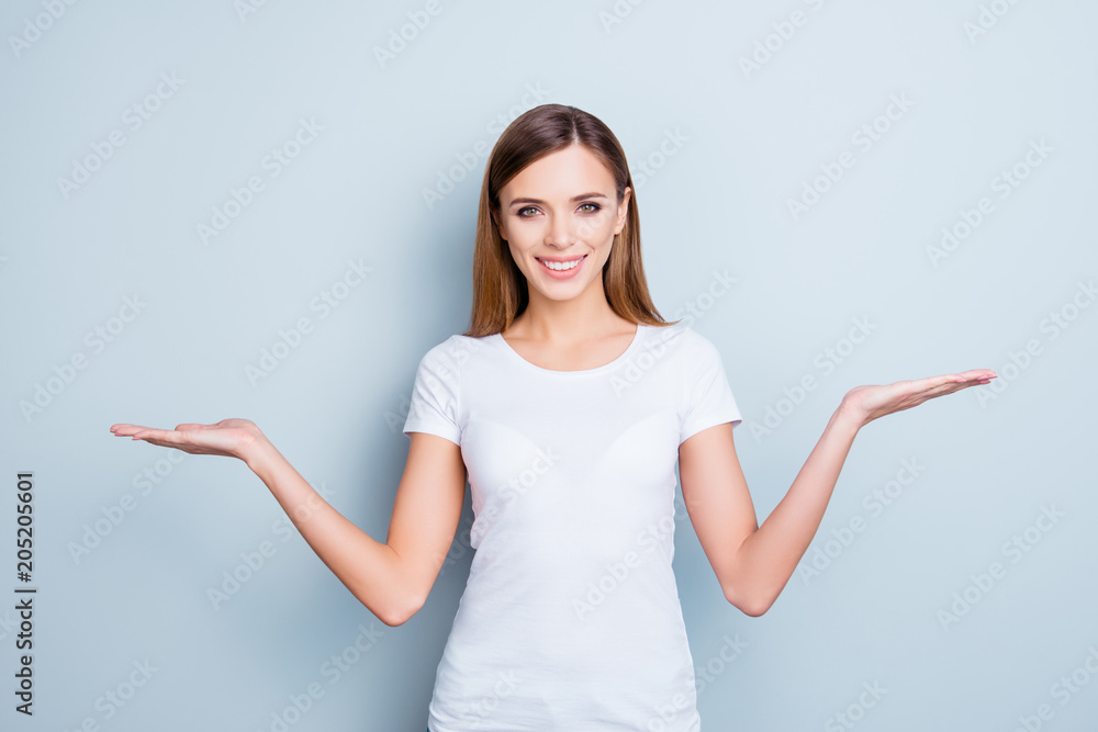 Portrait of charming gorgeous girl in white t-shirt gesturing empty place, copyspace on two palms looking at camera isolated on grey background Portrait of charming gorgeous girl in white t-shirt gesturing empty place, copyspace on two palms looking at camera isolated on grey background