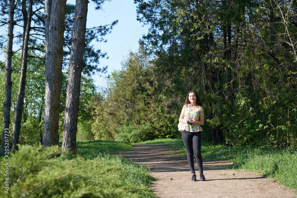young girl walking in spring forest with camera and taking pictures young girl walking in spring forest with camera and taking pictures