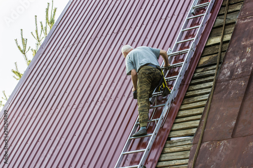 A man is repairing a roof standing on the stairs