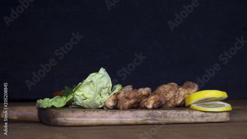 Breaded Chicken Meat With Salad And Lemon Resting On a Rustic Wooden Board photo