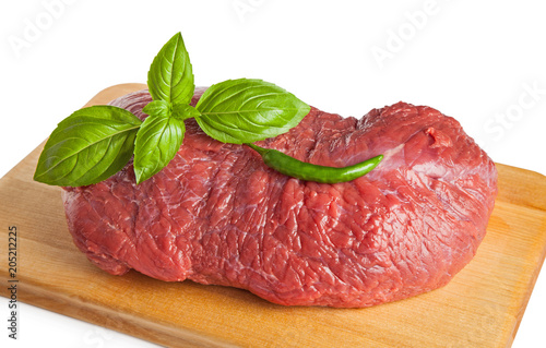 Raw, whole beef with basil and chilli on a board, isolated on a white background.