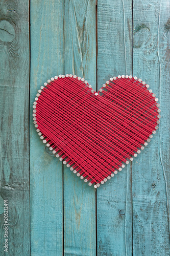 Decorative heart made of thread on a wooden background