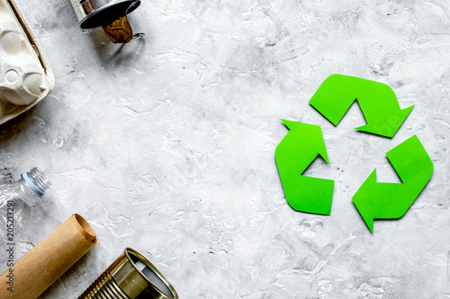 waste recycling symbol with garbage on stone background top view