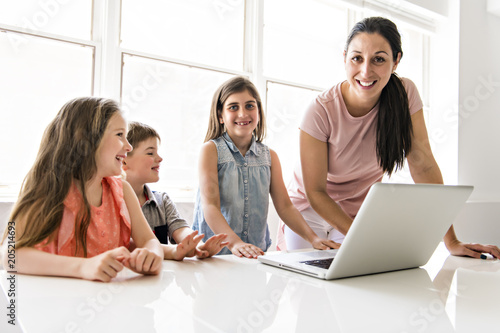 Teacher with a group of school children with laptop on the front