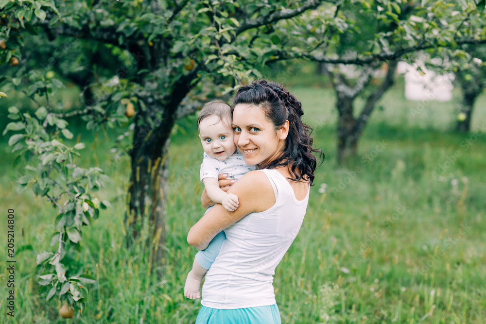 Happy family. Smiling mother holding her cute little son in the park Happy family. Smiling mother holding her cute little son in the park