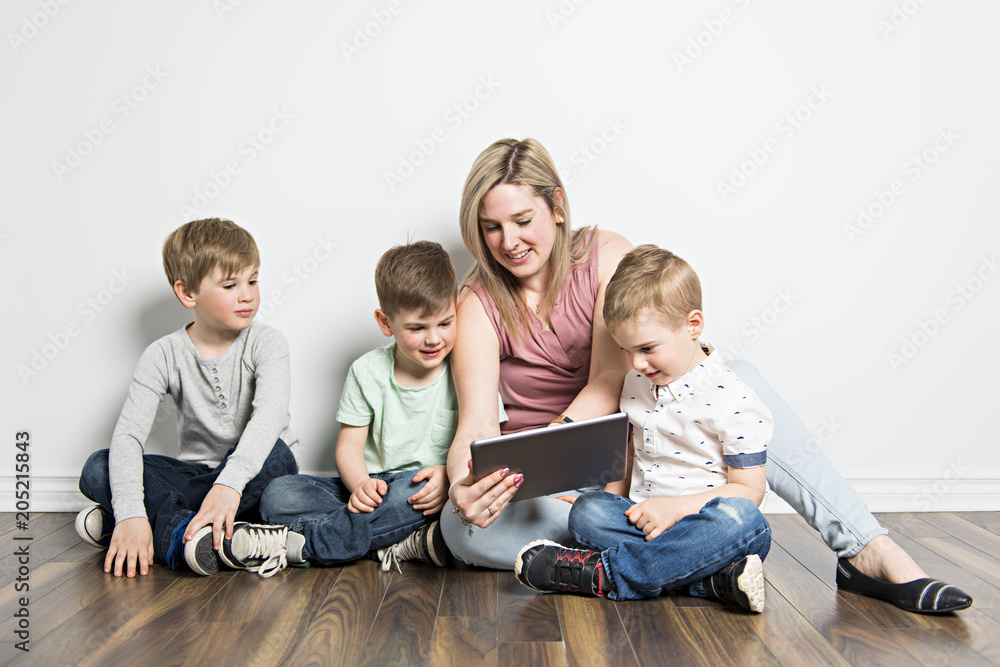 girls and her mom are sitting on the floor, using a digital tablet