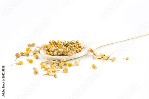 Dried camomile on a wooden spoon isolated on a white background