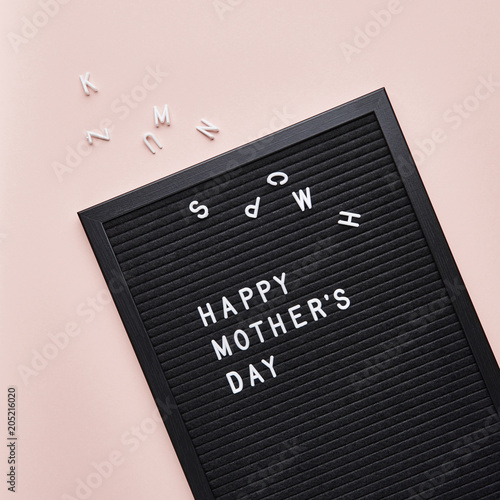 Black letterboard with white plastic letters with quote Happy Mother's Day, on pink background.