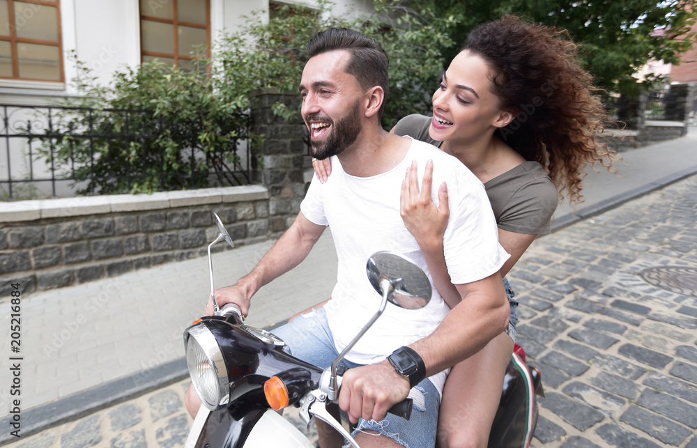 Obraz premium Young couple riding motor scooter in city