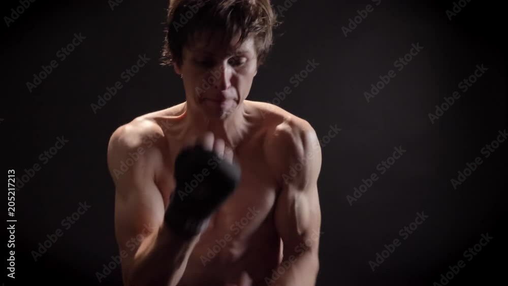 Portrait of a young caucasian topless male boxer, boxing, fight with shadow, training, black background 50 fps Portrait of a young caucasian topless male boxer, boxing, fight with shadow, training, black background 50 fps