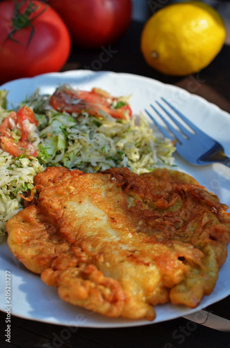 Fried fish in dough with salad on a white plate