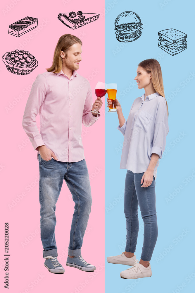 Romantic date. Full length of young pleasant couple spending time together while drinking beer and wine on colored background Romantic date. Full length of young pleasant couple spending time together while drinking beer and wine on colored background