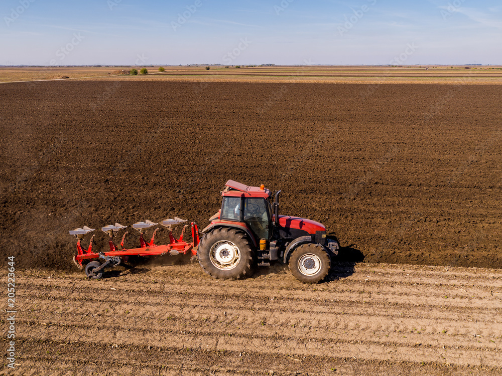 Obraz premium Aerial shot of a farmer plowing stubble field