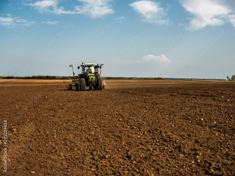 Fototapeta premium Farmer seeding, sowing crops at field. Sowing is the process of planting seeds in the ground as part of the early spring time agricultural activities.
