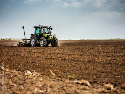 Farmer seeding  sowing crops at field. Sowing is the process of planting seeds in the ground as part of the early spring time agricultural activities.