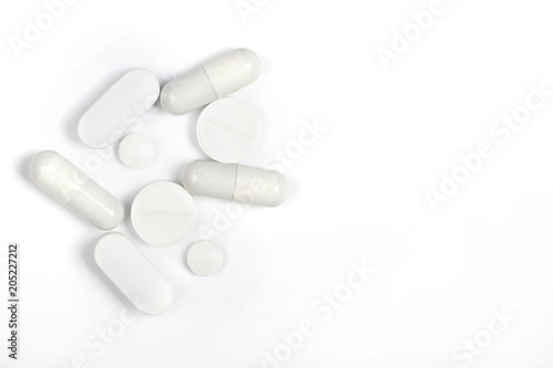 round and oval white pills  and capsules on a white background