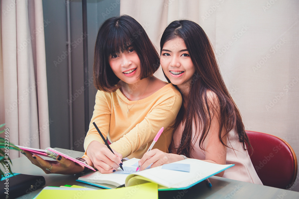 Portrait of smiling two students at work in a library. Portrait of smiling two students at work in a library.