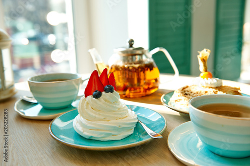 meringue with cream and strawberries with a cup of tea  teapot in the cafe