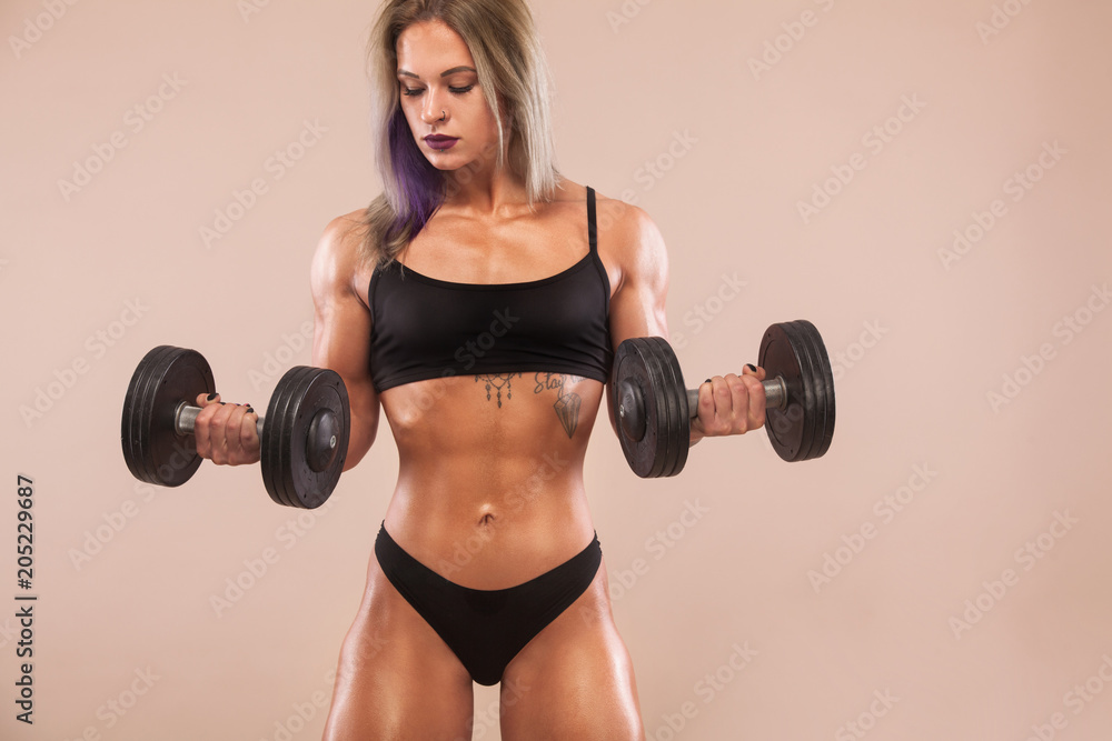 Muscular young fitness sports woman with strong fit body on light background. Muscular young fitness sports woman with strong fit body on light background.