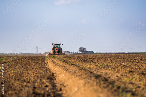 Farmer in tractor preparing land with seedbed cultivator as part of pre seeding activities in early spring season of agricultural works at farmlands. © oticki