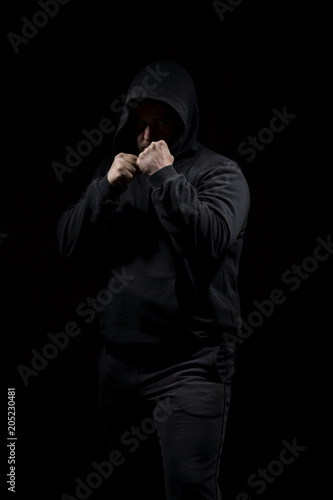 Male adult with black hoodie on black background. High resolution image concept for boxing and fighting industry.
