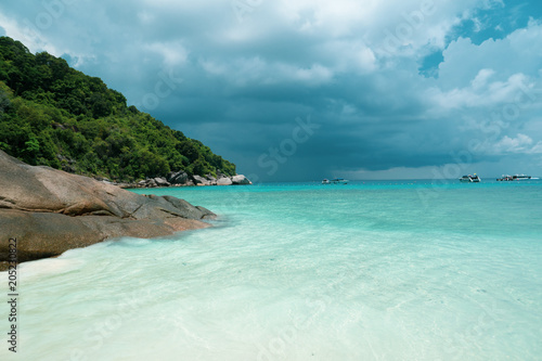 White sandy tropical beach over beautiful sea and cloudy sky background