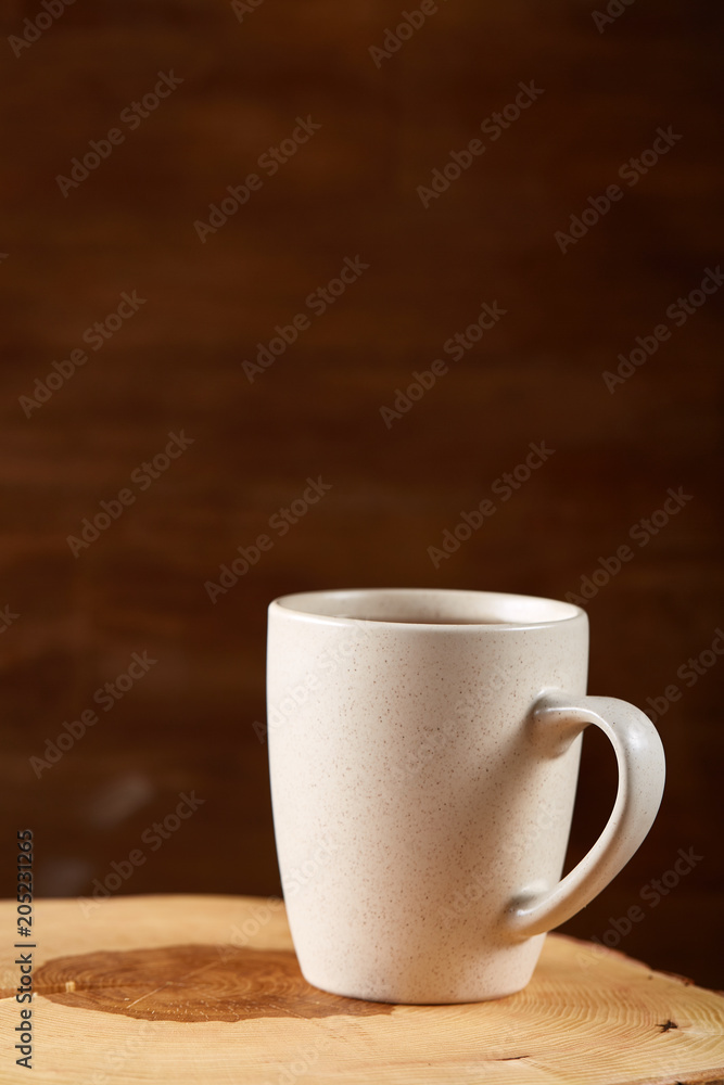 White cup of hot tea on an old log over rustic wooden background, selective focus White cup of hot tea on an old log over rustic wooden background, selective focus