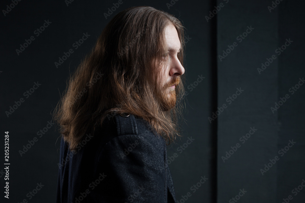 Portrait of man with long hair and beard in black clothes on dark background Portrait of man with long hair and beard in black clothes on dark background