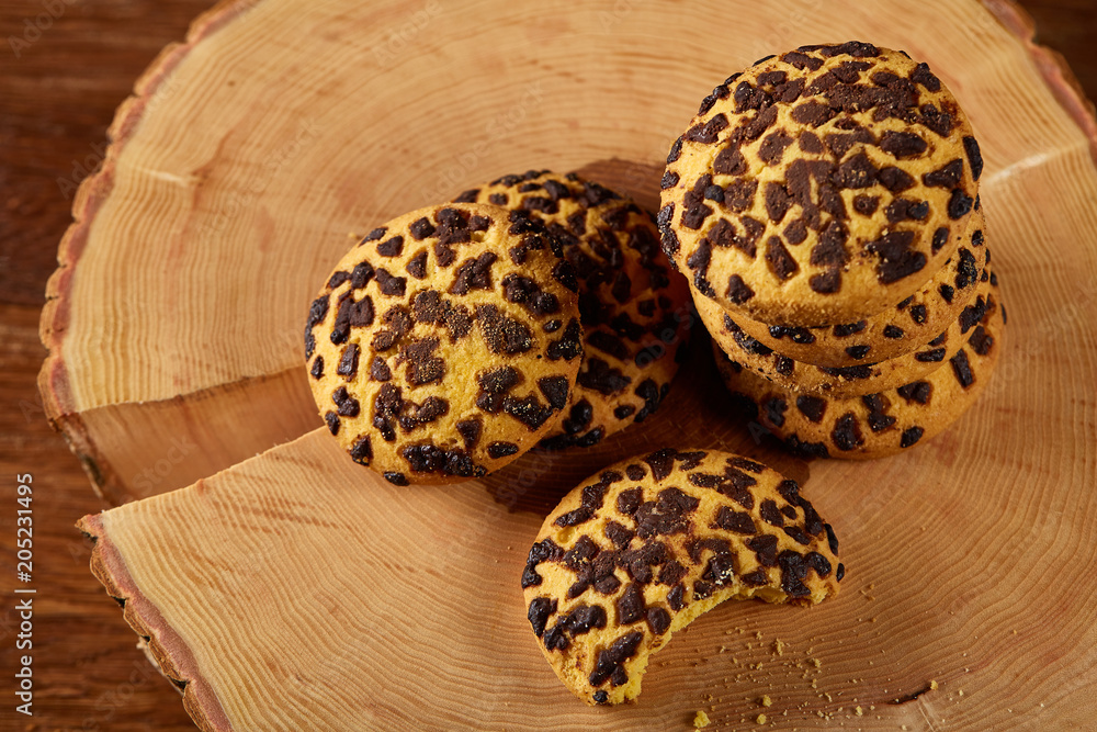 Pile of biscuits on a round wood log over rustic wooden background, close-up, selective focus. Pile of biscuits on a round wood log over rustic wooden background, close-up, selective focus.
