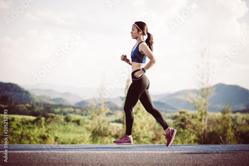 Young woman running outdoors at sunrise or sunset. Wellness and health concept.
