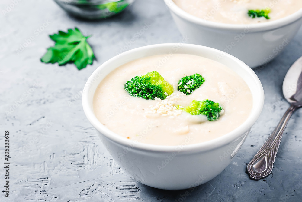 Garlic, parsnip white bean broccoli soup puree in a bowl on blue concrete background. Selective focus, space for text. Garlic, parsnip white bean broccoli soup puree in a bowl on blue concrete background. Selective focus, space for text.