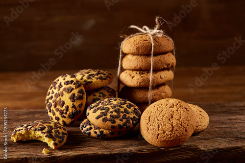 Fotografija Sweet assortment of biscuits on a round wood log over rustic wooden background, close-up, selective focus
