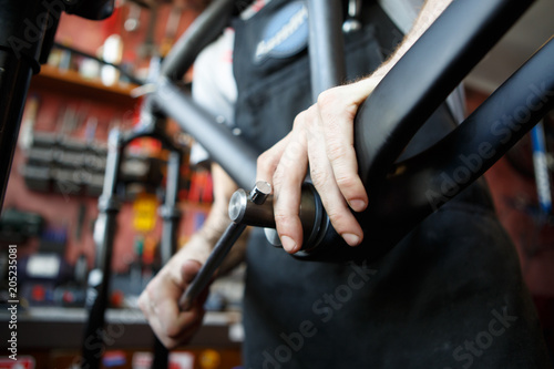 Picture of man mending part of bicycle in workshop.