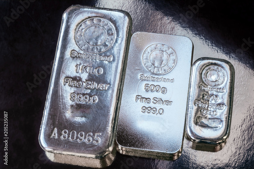 Three silver bars of different weight. The surface of cast silver bullion. photo