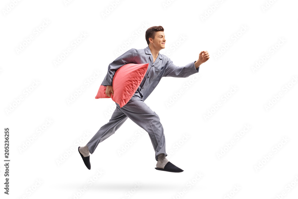 Teenage boy in pajamas holding a pillow and running Teenage boy in pajamas holding a pillow and running