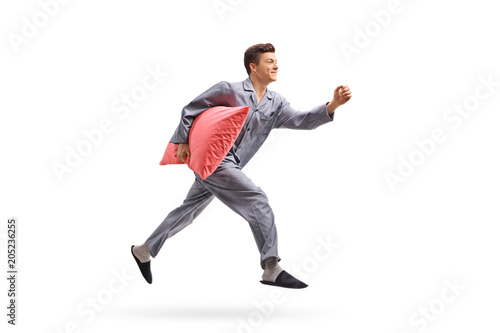 Teenage boy in pajamas holding a pillow and running