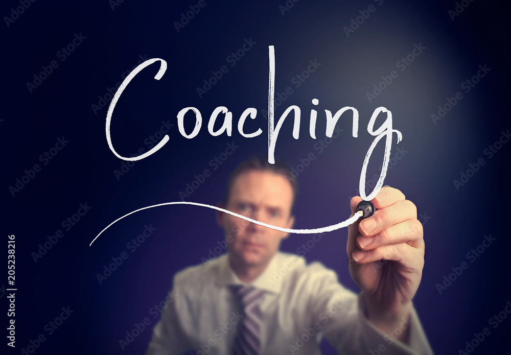 A businessman writing a Coaching concept with a white pen on a clear screen. A businessman writing a Coaching concept with a white pen on a clear screen.