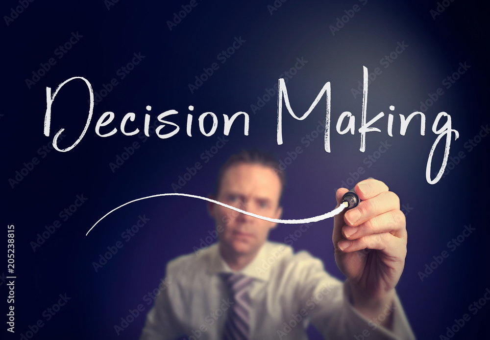 A businessman writing a Decision Making concept with a white pen on a clear screen. A businessman writing a Decision Making concept with a white pen on a clear screen.