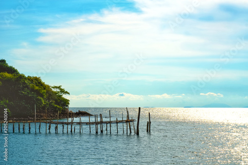 Vacation time concept, A view of old wooden bridge in the sea and blue sky on background © Panupat