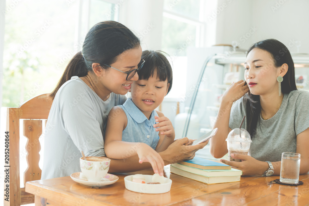 mother and daughter read a book drinking tea and cuddling in cafe mother and daughter read a book drinking tea and cuddling in cafe