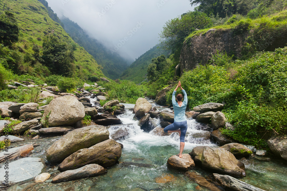Woman in yoga asana Vrikshasana tree pose at waterfall outdoors Stock ...