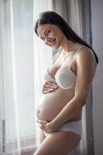 Free Download Pregnant happy woman in underwear by the window with curtains - GFXLoad